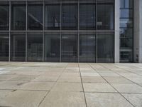 this is a view of an empty patio outside an office building with windows, and a door open