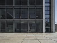 this is a view of an empty patio outside an office building with windows, and a door open