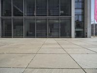 this is a view of an empty patio outside an office building with windows, and a door open