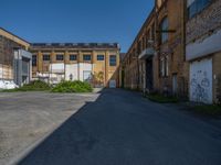 an empty and deserted alley in a large industrial building with graffiti on it's side