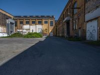 an empty and deserted alley in a large industrial building with graffiti on it's side