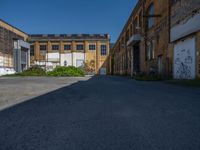 an empty and deserted alley in a large industrial building with graffiti on it's side