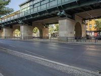 a large bridge over the street, near many bike racks on the side of the road