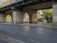 a large bridge over the street, near many bike racks on the side of the road