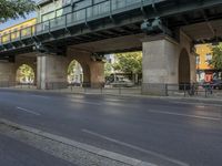 a large bridge over the street, near many bike racks on the side of the road