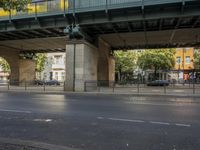 a large bridge over the street, near many bike racks on the side of the road