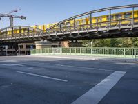 a long yellow train is going over the bridge to the station on a sunny day