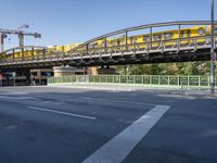 a long yellow train is going over the bridge to the station on a sunny day