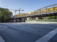 a long yellow train is going over the bridge to the station on a sunny day