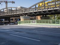 a long yellow train is going over the bridge to the station on a sunny day