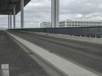 a man in the middle of the highway driving past tall buildings with metal fences around it