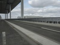 a man in the middle of the highway driving past tall buildings with metal fences around it