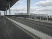a man in the middle of the highway driving past tall buildings with metal fences around it