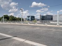 the empty roadway is full of bicycles, with buildings in the background and cars parked along the side