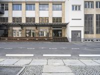 an empty building with signs on the street and people on bikes in traffic passing by