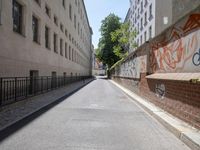 a paved roadway is lined with tall buildings and grafitti - like graffiti on the walls