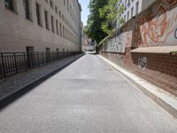 a paved roadway is lined with tall buildings and grafitti - like graffiti on the walls