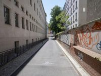 a paved roadway is lined with tall buildings and grafitti - like graffiti on the walls