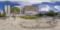 fisheye photo of the abandoned building and parking lot with graffiti all over it that is full of trash