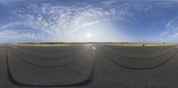 a panoramic view of an empty runway of tarmac near a dirt field