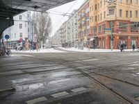 a street with a light in the middle of the street covered in snow and some people