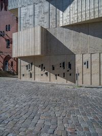 cobblestone driveway surrounded by modern buildings on sunny day with sun reflecting onto the windows