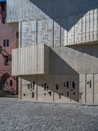 cobblestone driveway surrounded by modern buildings on sunny day with sun reflecting onto the windows