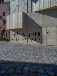 cobblestone driveway surrounded by modern buildings on sunny day with sun reflecting onto the windows