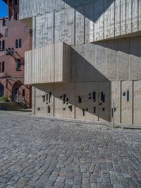 cobblestone driveway surrounded by modern buildings on sunny day with sun reflecting onto the windows