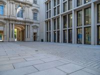 an empty brick courtyard area with two stone columns and two arched windows in the background