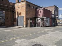 a brick building with graffiti written on it and a fence surrounding the building and building