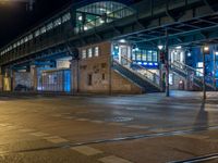 the empty street is filled with people walking and biking under an overpass at night