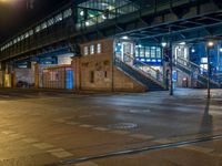 the empty street is filled with people walking and biking under an overpass at night