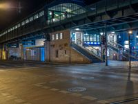 the empty street is filled with people walking and biking under an overpass at night