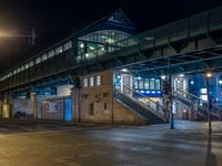 the empty street is filled with people walking and biking under an overpass at night