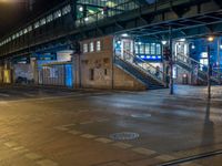 the empty street is filled with people walking and biking under an overpass at night