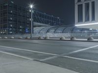 the empty city road is empty by the tall building in the background at night with light streaking on the buildings