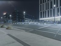 the empty city road is empty by the tall building in the background at night with light streaking on the buildings