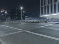 the empty city road is empty by the tall building in the background at night with light streaking on the buildings