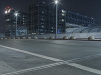 the empty city road is empty by the tall building in the background at night with light streaking on the buildings