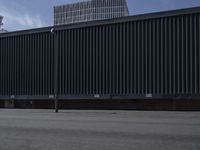 an empty parking lot with a large black fence in the background and tall buildings on both sides