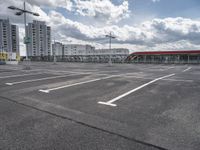 an empty parking lot with a number one across from it, and some buildings in the background