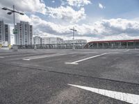 an empty parking lot with a number one across from it, and some buildings in the background