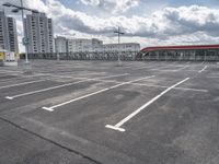 an empty parking lot with a number one across from it, and some buildings in the background