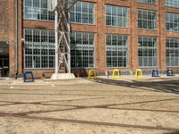 a bunch of yellow chairs sitting in front of a building that has a metal structure on it's side