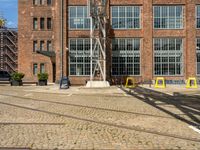 a bunch of yellow chairs sitting in front of a building that has a metal structure on it's side