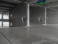 an empty concrete garage with signs on the ceiling and exit doors that lead out to an empty area