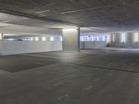 an empty parking garage with light colored concrete floors and cement walls that have yellow paint on them