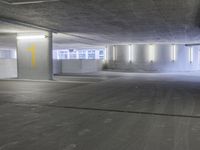 an empty parking garage with light colored concrete floors and cement walls that have yellow paint on them