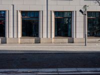 a sidewalk with a bench and brick sidewalk and building with a sky background and reflection on water